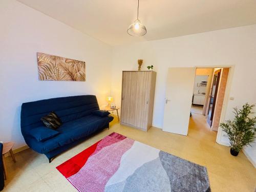 Una sala de estar con un sofá azul y una alfombra. en Le pied à terre - Centre ville - Montceau-les-mines, en Montceau-les-Mines