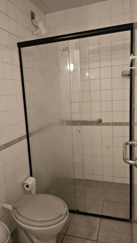 a bathroom with a toilet and a glass shower at Flor de Laranjeira Guest House in São Pedro da Aldeia