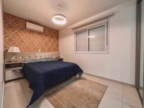 ein Schlafzimmer mit einem blauen Bett und einem Fenster in der Unterkunft 2 Dorm a 100 metros do mar in Capão da Canoa