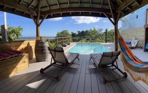 a deck with two chairs and a hammock next to a pool at La Maison d'Abigaelle in Le François