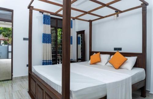 una camera con letto a baldacchino e cuscini arancioni di Blue Heaven Villa ad Ahangama