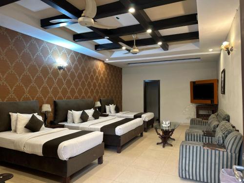 a hotel room with three beds and a tv at Royal Ilva Hotel in Lahore