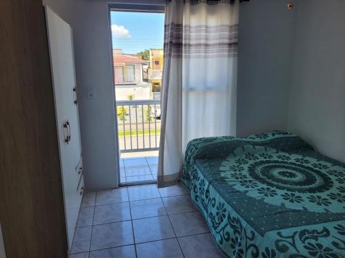 une chambre avec un lit et une grande fenêtre dans l'établissement Kit net familia, à São Francisco do Sul