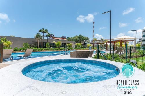Refúgio Verão - Flat de alto padrão na praia do Cupe - Porto de Galinhas في بورتو دي غالينهاس: مسبح دائري كبير مزود بكراسي وطاولة