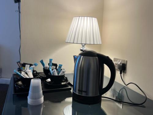 a coffee pot sitting on a table with a lamp at Osterley Park Hotel in Syon Lane Station