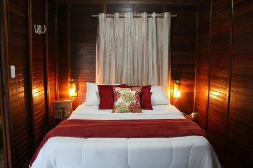 a bedroom with a large bed with wooden walls at Chalé Ipê Amarelo in Juquitiba