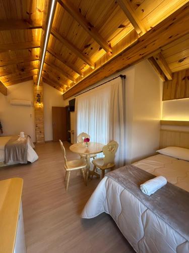 a bedroom with a bed and a table and chairs at Pousada Pattis in Treze Tílias