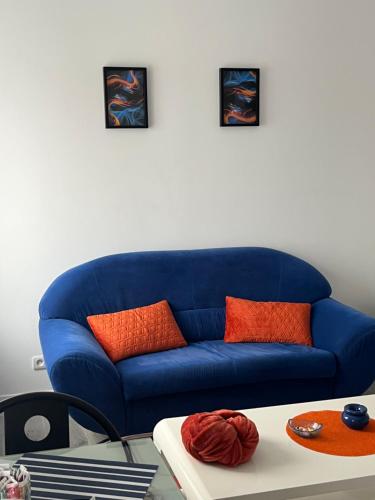 een blauwe bank met oranje kussens in de woonkamer bij Violette 2 in La Souterraine