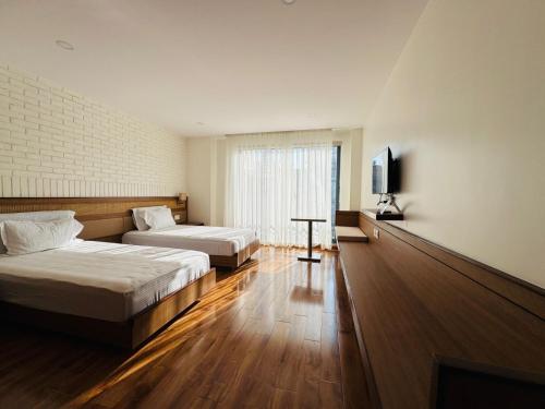 パタンにあるNavaya Residenceのベッド2台とテレビがあるホテルの部屋