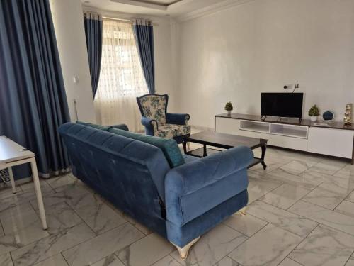 een woonkamer met een blauwe bank en een tafel bij The DomeApp Apartment in Kumasi