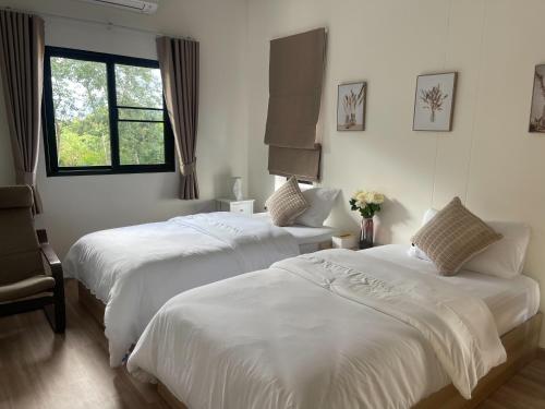 two beds in a room with white sheets and a window at Sleep Shot Pool Villa in Ban Fang Min