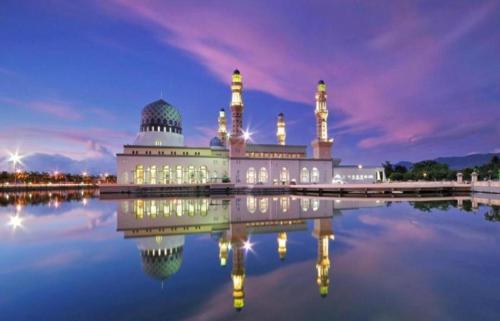a mosque with its reflection in the water at night at The Shore in Kota Kinabalu