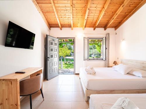 a bedroom with two beds and a desk and a television at Janakis Garden Livadi Beach in Spile