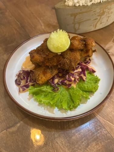 a plate of food with chicken wings and salad on a table at Tropictide Weligama in Nikawatawana