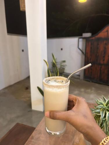 a hand holding a glass with a drink at Tropictide Weligama in Nikawatawana