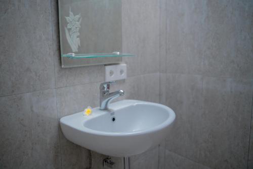 a white sink in a bathroom with a mirror at Padma Graha Villa in Candidasa