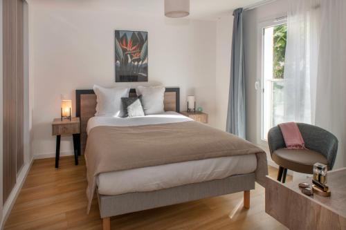 a bedroom with a bed and a chair and a window at Domitys L'Ellipse in Paris
