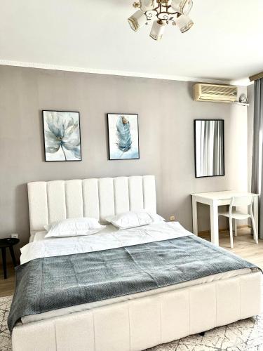 a white bed in a bedroom with two pictures on the wall at 1 комнатные апартаменты in Atyraū