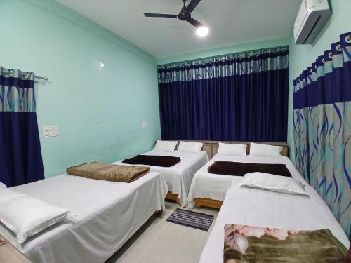 three beds in a room with blue walls at Shree DashbhujaNath Stays in Ujjain