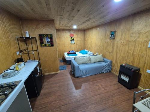 a living room with a couch in a room with wooden walls at Cabañas Tupananchiskama in Ancud