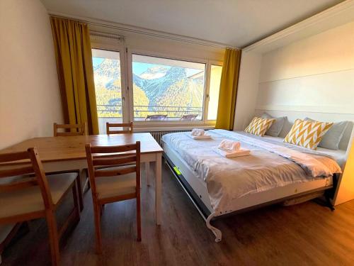 ein Schlafzimmer mit Bett, Schreibtisch und Fenster in der Unterkunft Fortuna 8 by Arosa Holiday in Arosa