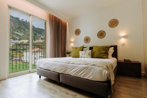 a bedroom with a large bed and a large window at Hotel Euro Moniz in Porto Moniz