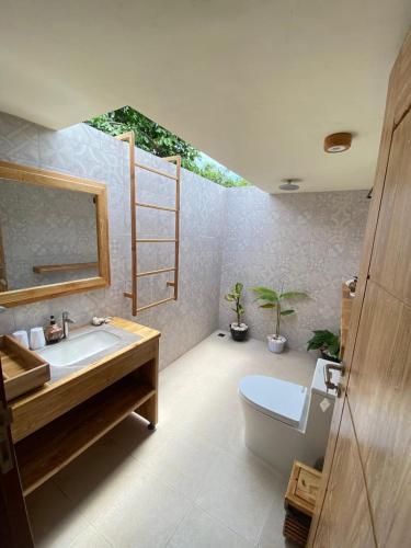 a bathroom with a sink and a toilet and a mirror at SA Oeona Bungalow in Nembrala