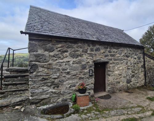 an old stone building with a door and some flowers at The Old Barn in Bettws Gwerfil Goch