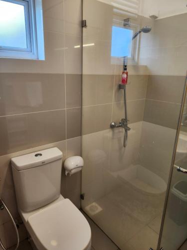 Un baño con inodoro y ducha con puerta de cristal. en Aqua Beach Resort Apartments, en Wattala