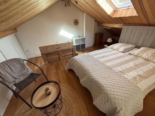 ein Schlafzimmer mit einem großen Bett und einem Stuhl in der Unterkunft Maisonnette à la campagne in Roissard