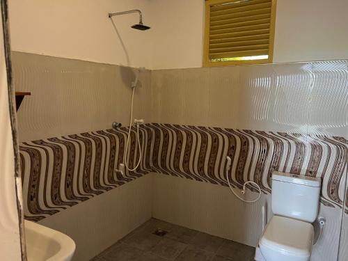 uma casa de banho com uma cortina de duche listrada e um WC em The Sunset Weligama em Weligama