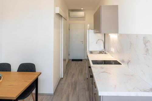 a kitchen with white marble countertops and a wooden table at Urban NEST apartment - FREE Parking & Central in Kočevje