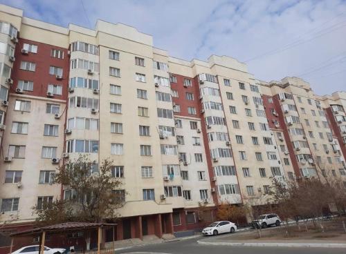 een groot appartementencomplex met auto's voor het gebouw bij 1 комн апартаменты в центре города in Atıraw