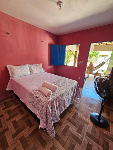 a bedroom with a bed with a red wall at Pousada Brilho do Mar in Guriú