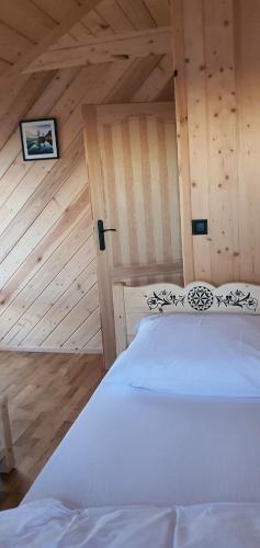 a bedroom with a white bed and a wooden wall at Bachledowy Wierch 1 in Czerwienne