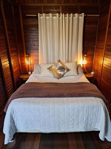 a bedroom with a large white bed with two pillows at Chalé Primavera in Juquitiba