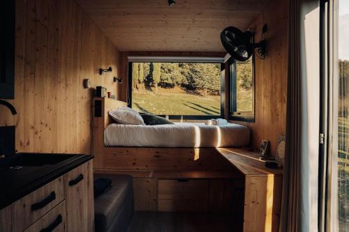 ein Schlafzimmer in einem winzigen Haus mit einem Fenster in der Unterkunft Parcel Tiny House Barroux, entouré par les lamas près du Mont Ventoux in Le Barroux