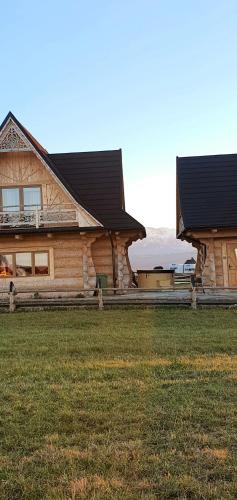 a large wooden house with a grass field in front of it at Bachledowy Wierch 1 in Czerwienne