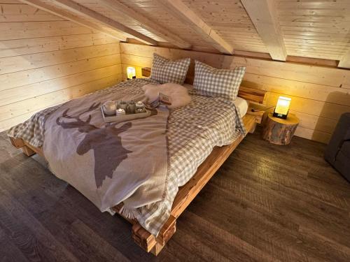 una cama en una cabaña con una persona puesta en ella en Harz-Blockhaus, Berg -"Hütte" mit Sauna und Kamin, en Hahnenklee-Bockswiese