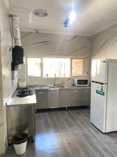 a kitchen with a white refrigerator and a sink at room near train station and airport in Perth