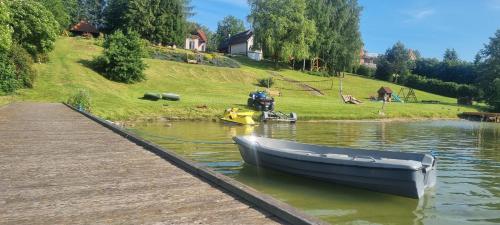 a boat sitting on the water next to a dock at Apartament nad Jeziorem Rybical 1 in Ryn