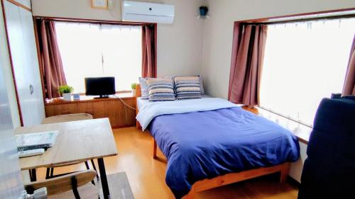 a bedroom with a bed and a desk and a tv at Kokusaigakusya Ozukikaikan - Vacation STAY 17510 in Hadano