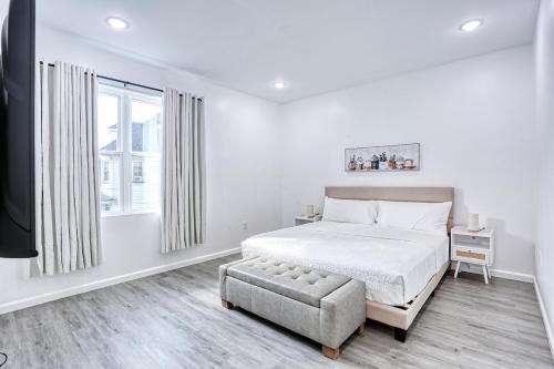 a white bedroom with a bed and a chair at Newly Built Lake House Near NYC EWR MetLife AD Mall in Passaic