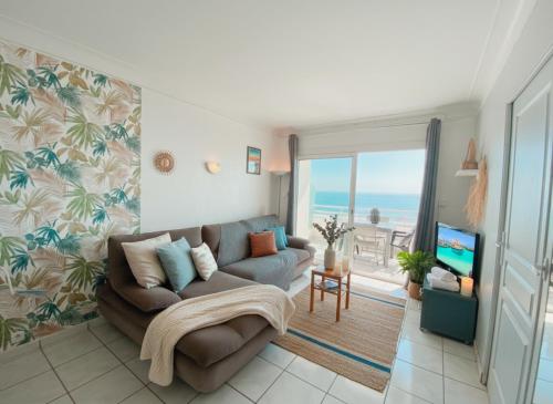 a living room with a couch and a tv at T3 Vue mer à couper le souffle in Canet-en-Roussillon