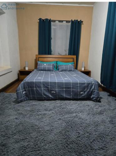 a bedroom with a bed with a blue comforter and blue curtains at Maison Andrianina in Ampitatafika