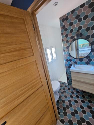 a bathroom with a wooden door and a toilet at La perle rare in Le Barcarès