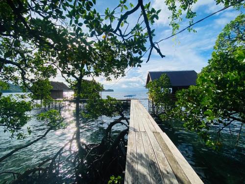 a wooden walkway over the water with a house at Batanta Guest House in Pulau Birie