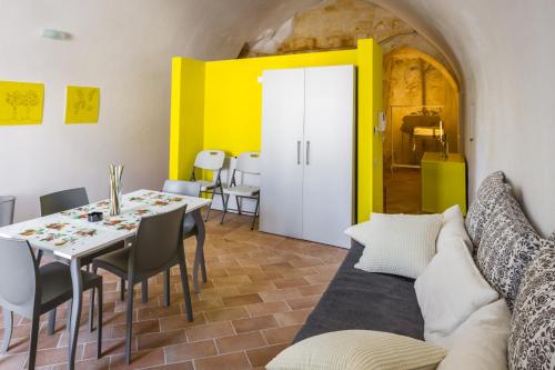 sala de estar con mesa y pared amarilla en Casamata Matera, en Matera