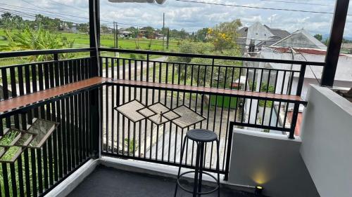 un balcón con un taburete y vistas a un campo en Villa 160 Prambanan, en Randugunting