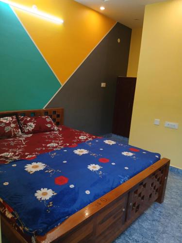 ein Schlafzimmer mit einem Bett mit einer blauen Decke mit Blumen in der Unterkunft Blueocean Residency in Virāmpattinam